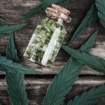 en glaskrukke fyldt med marihuanablade oven på et træbord.